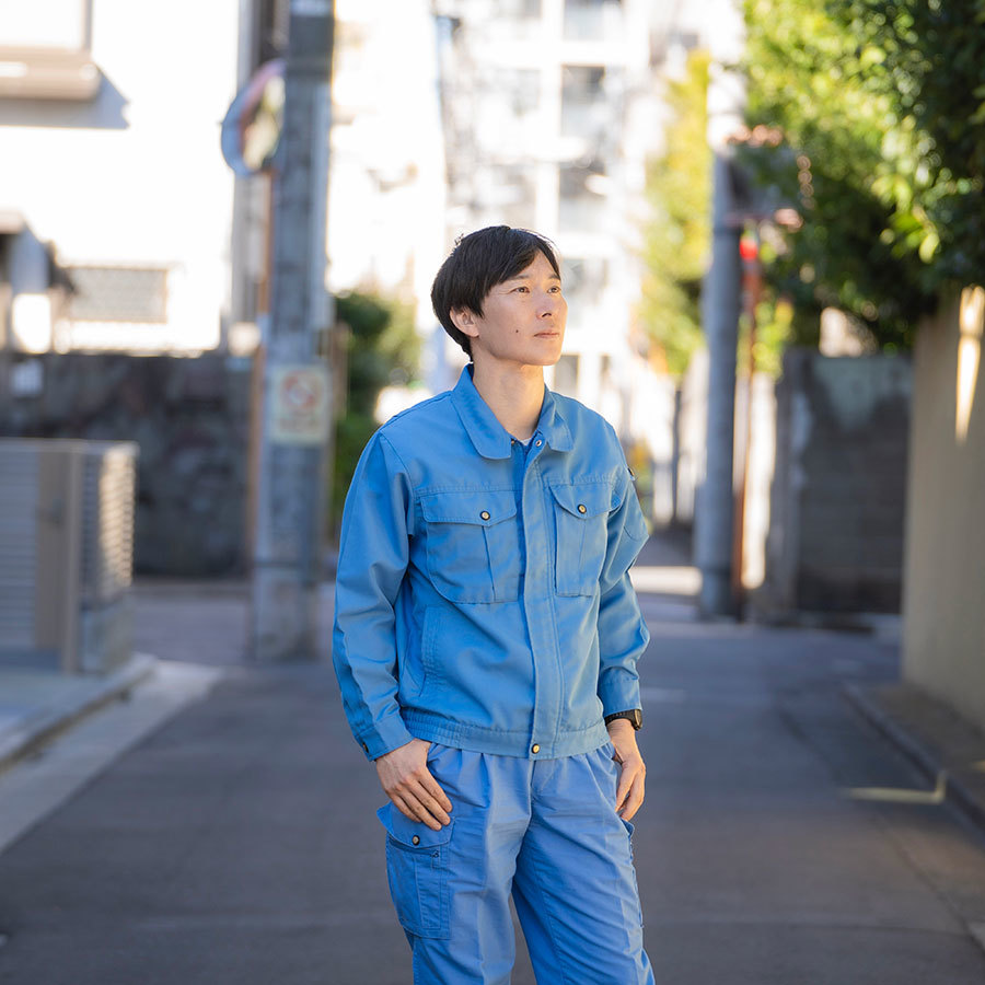 住宅街で遠くを見つめる滝沢さん。