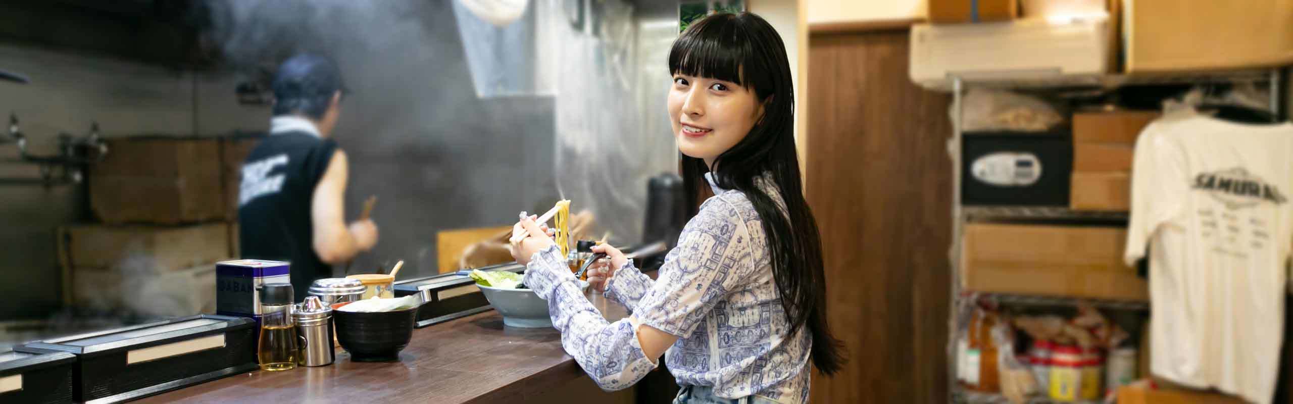 ラーメンを食べながらほほ笑むキャ・ノンさん。