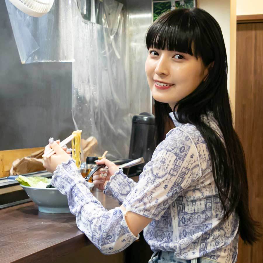 ラーメンを食べながらほほ笑むキャ・ノンさん。