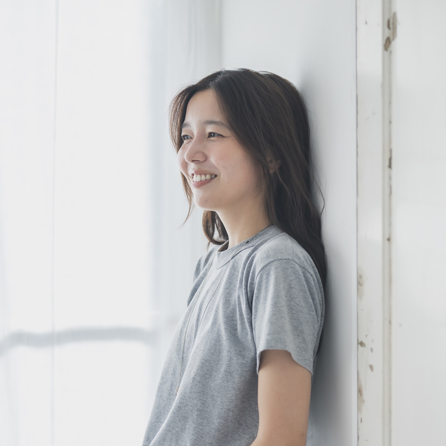 ドアに寄りかかりながらカメラのほうに目線を向けてやさしく笑うharu.さん。