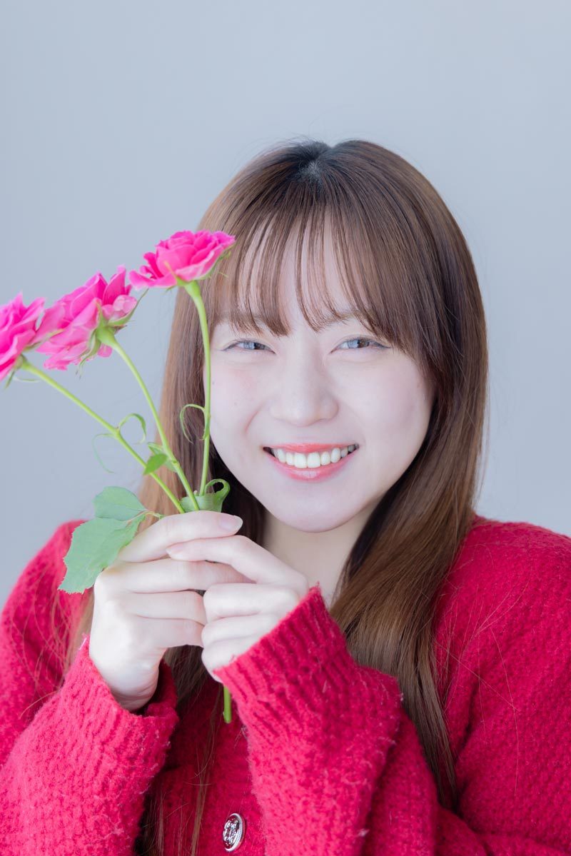 ピンク色の花を持って笑う中川さん。