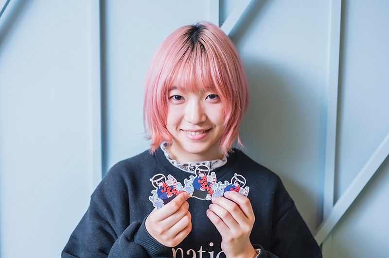 オリジナルステッカーを手に微笑むたむらかえさん。
