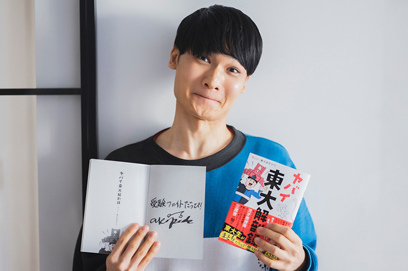著書『ヤバイ東大解剖録』を手にするあきぴでさん。