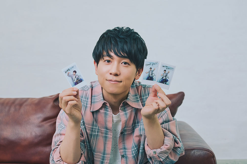 サイン入りチェキを手にほほ笑む山下さん。