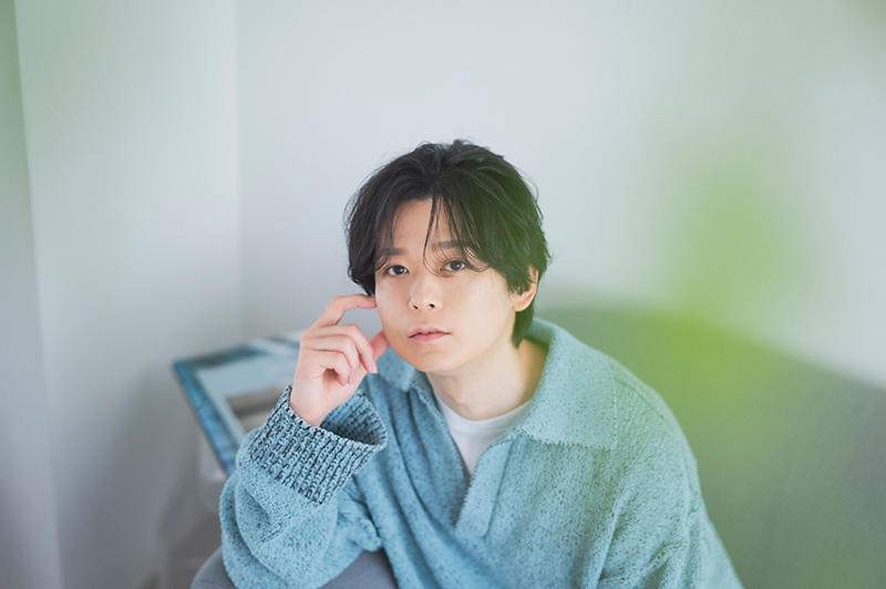 ソファに座ってポーズをとる土岐さん。