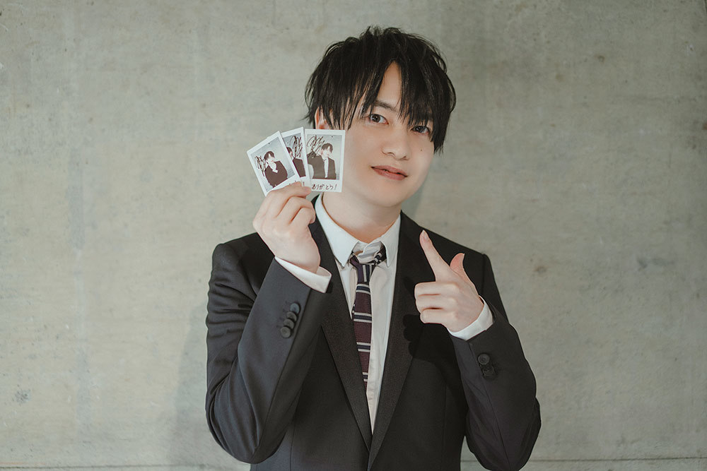 サイン入りチェキを手にほほ笑む小林さん。