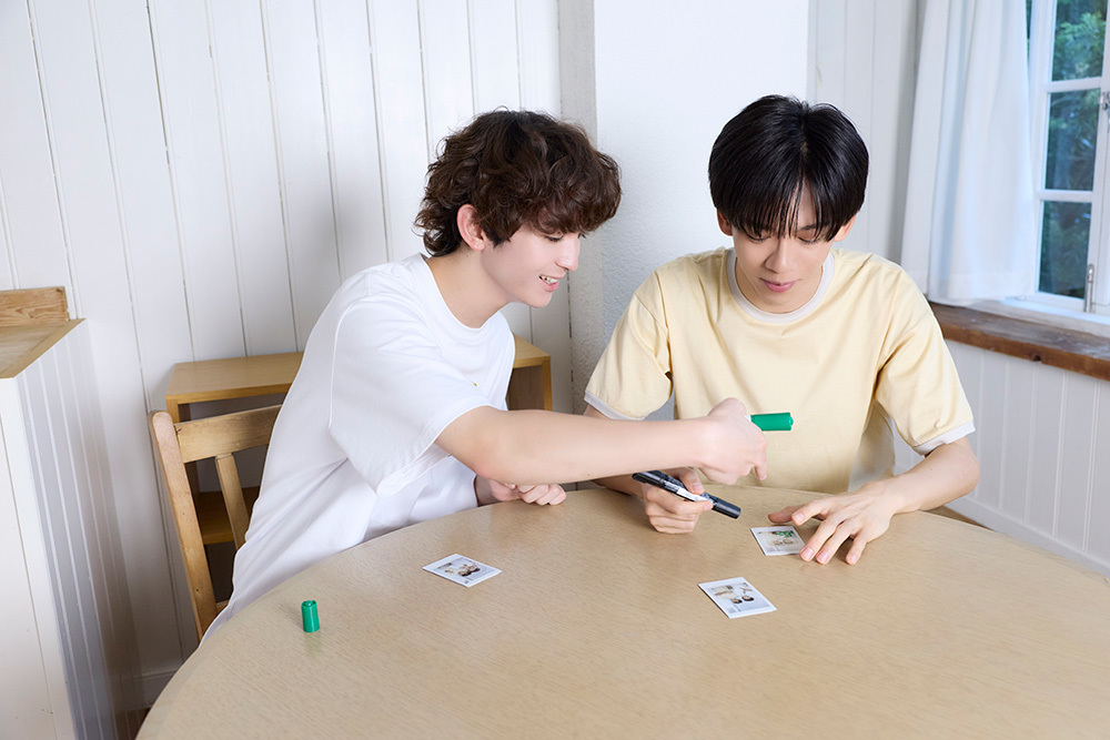 チェキにサインするリョウガさんとミロさん。