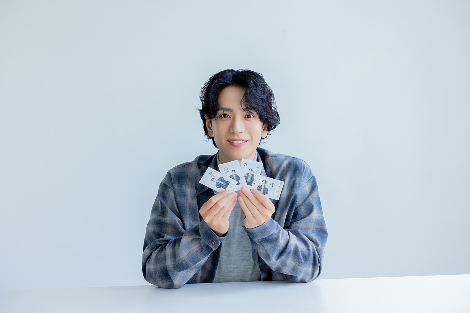 サイン入りチェキを手にカメラを見つめる黒羽さん。