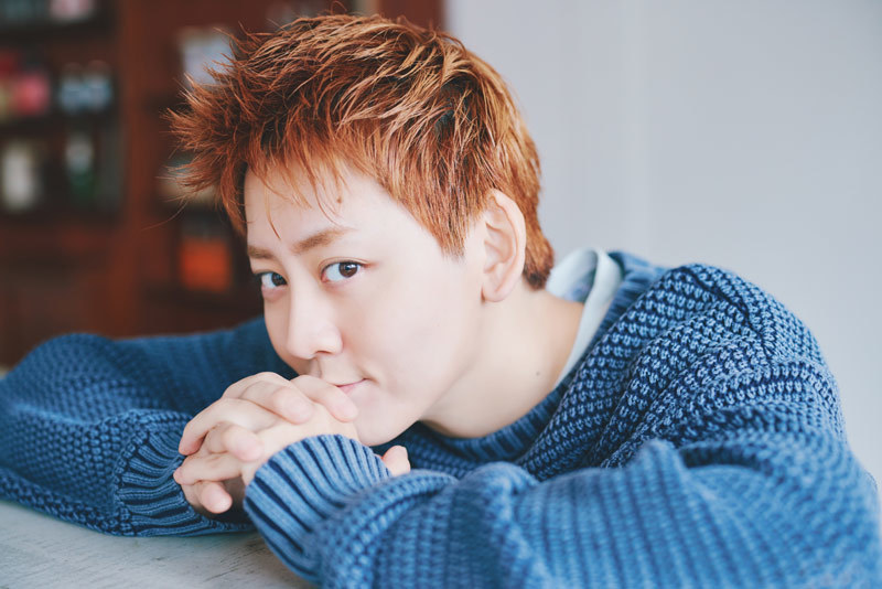 両手を組んでこちらを見つめる牧島さん。