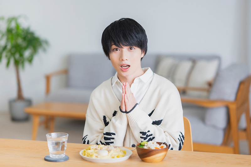 ダイニングテーブルでいただきますポーズをする植田さん。