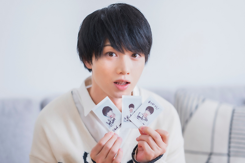 サイン入りチェキを手にカメラを見つめる植田さん。